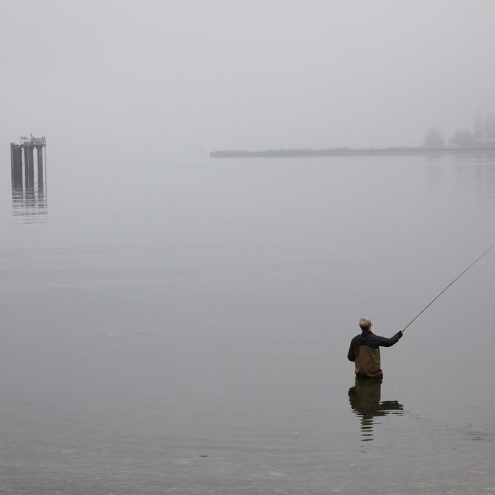 Woman fly fishing in fog. Eagle Harbor, Bainbridge Island, Washington.